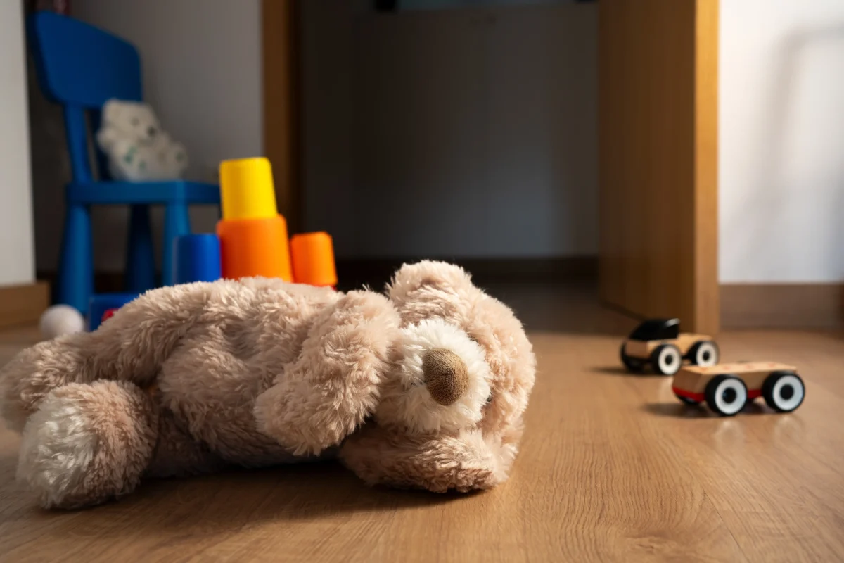 Na zemi leží pohozený medvídek. 