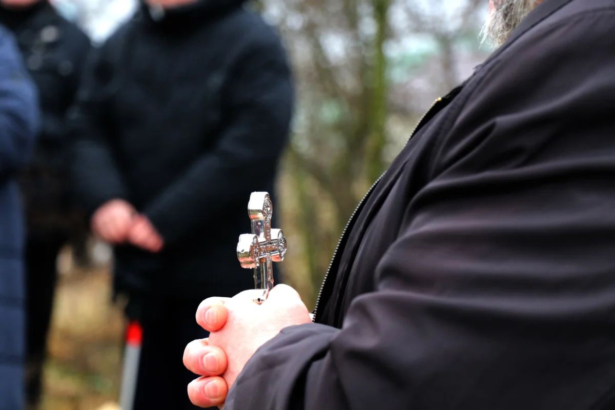 Muž v ruce drží kříž.