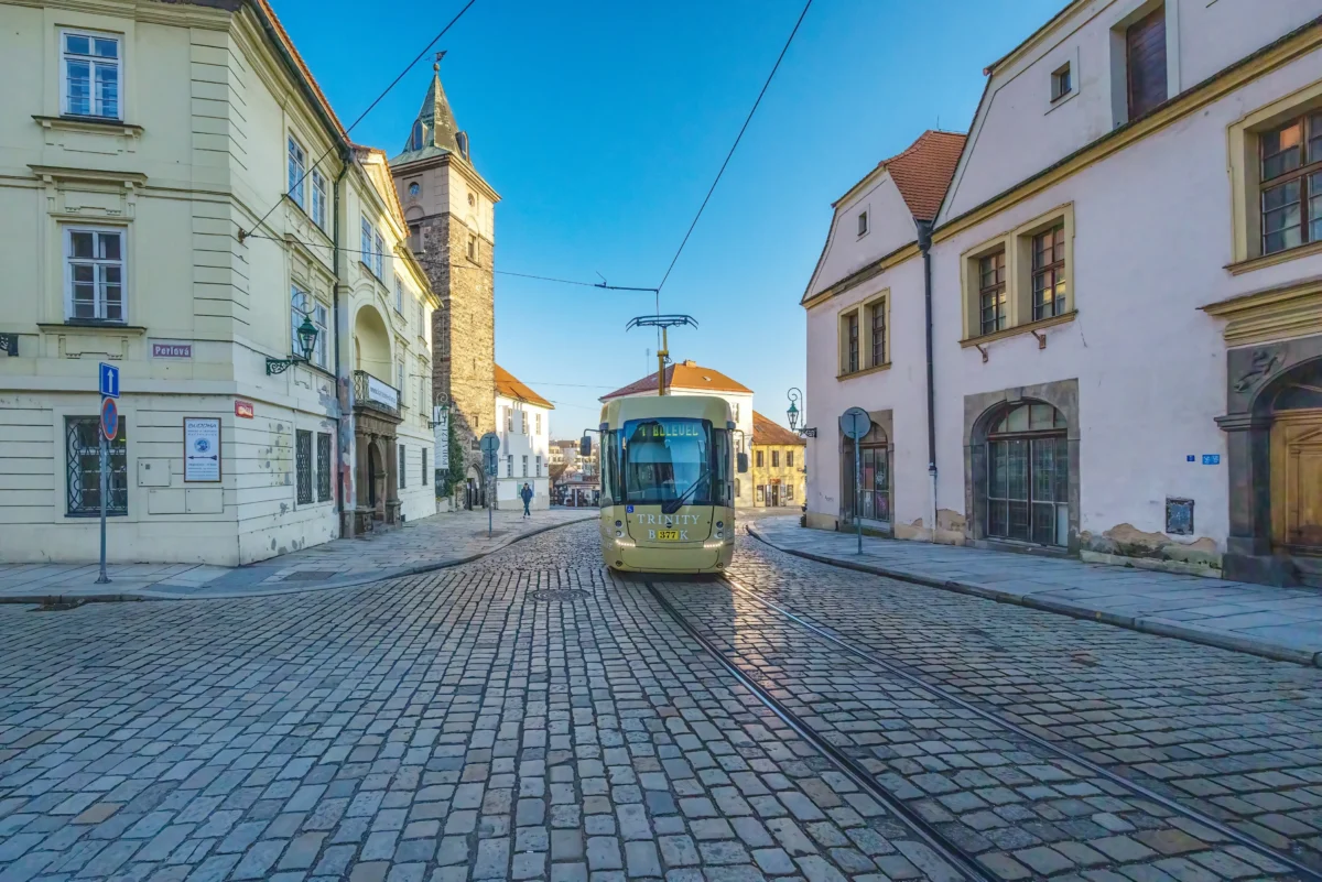 Ulicí Plzně jede tramvaj. 