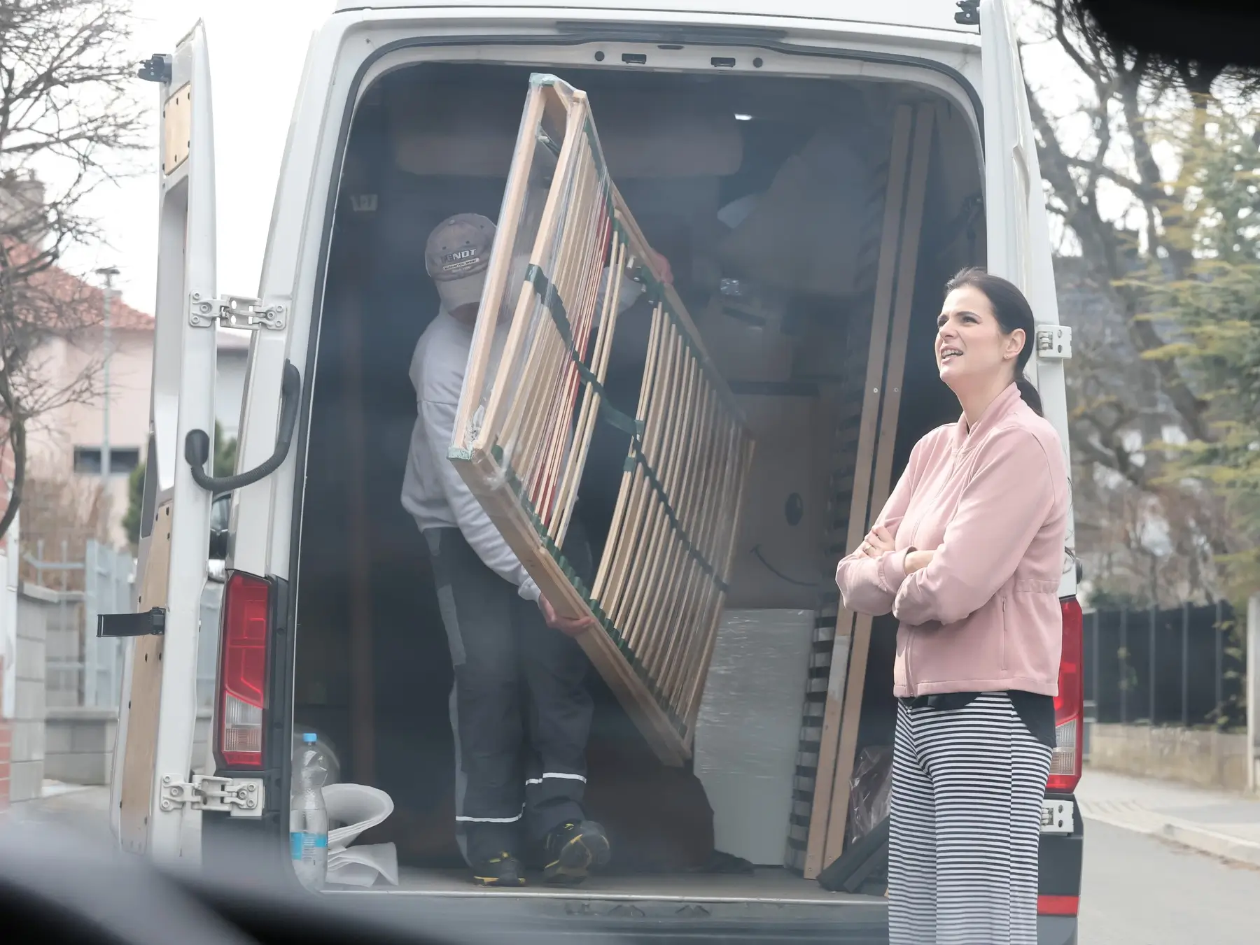 Ornella Koktová stojí u auta, ze kterého muž tahá rošt.