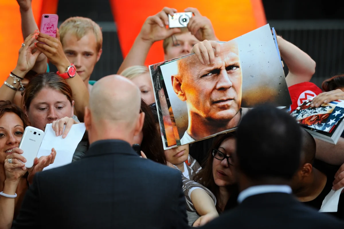 shutterstock_2601457929 | TVGURU.cz Bruce Willis je obklopený davem diváků.