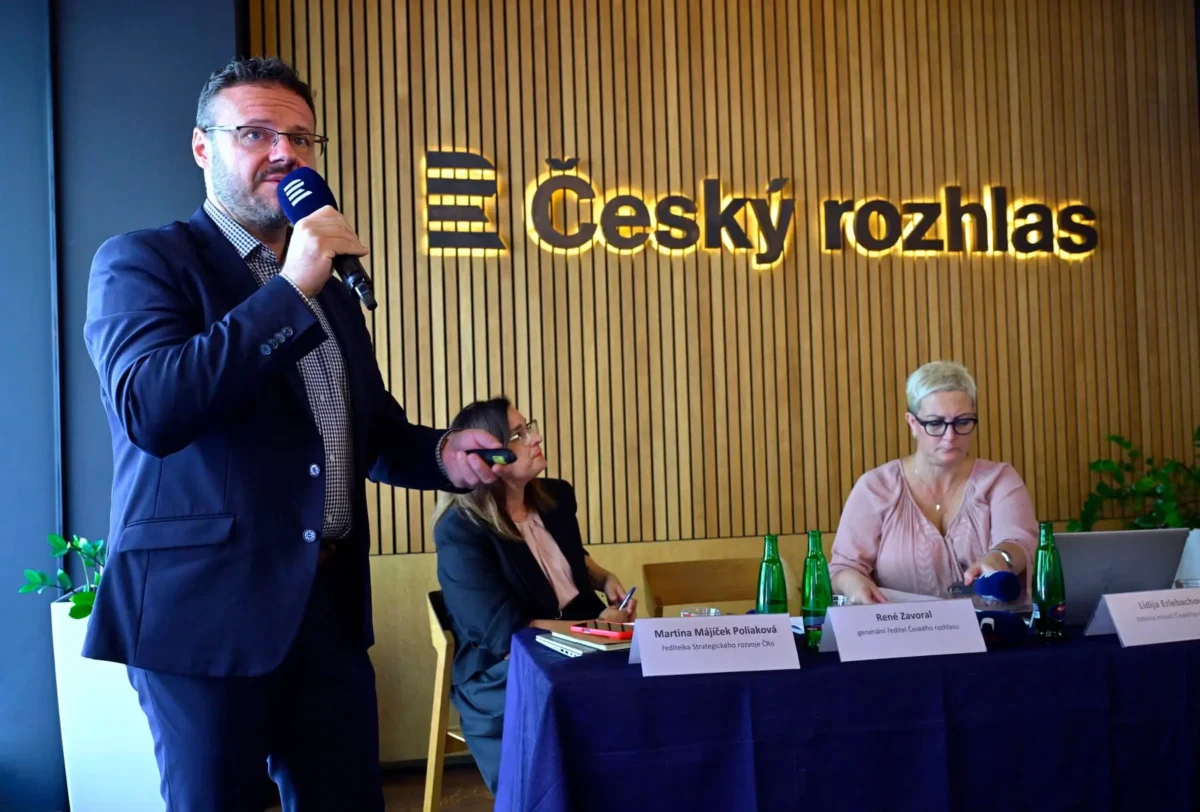 muž s mikrofonem u stolku