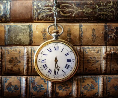 Před starými knihami visí hodiny.