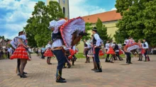 Lidé vystupují v krojích.