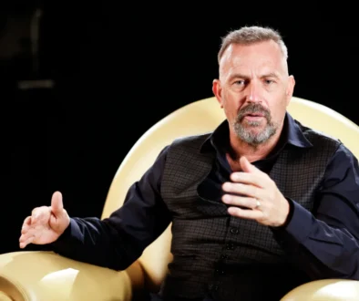 Kevin Costner sedí v křesle.