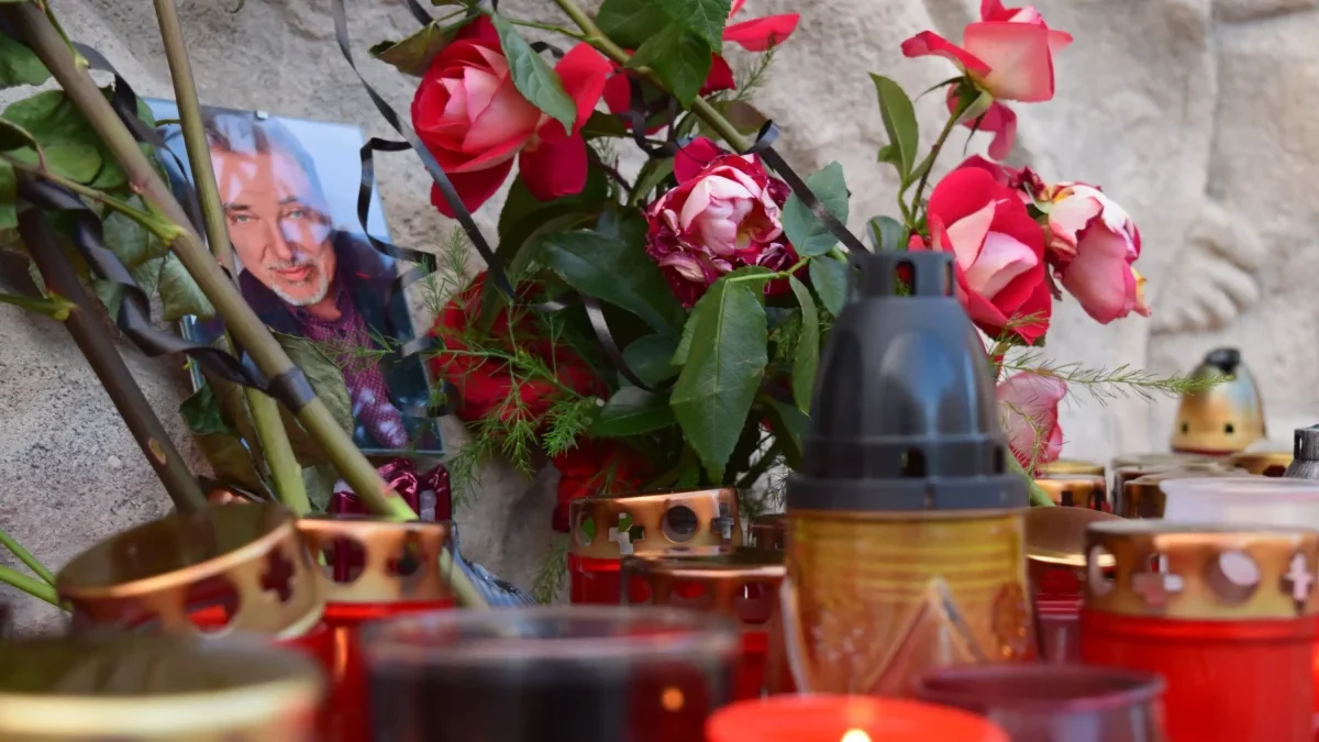 Kolem fotky Karla Gotta leží květiny a svíčky.
