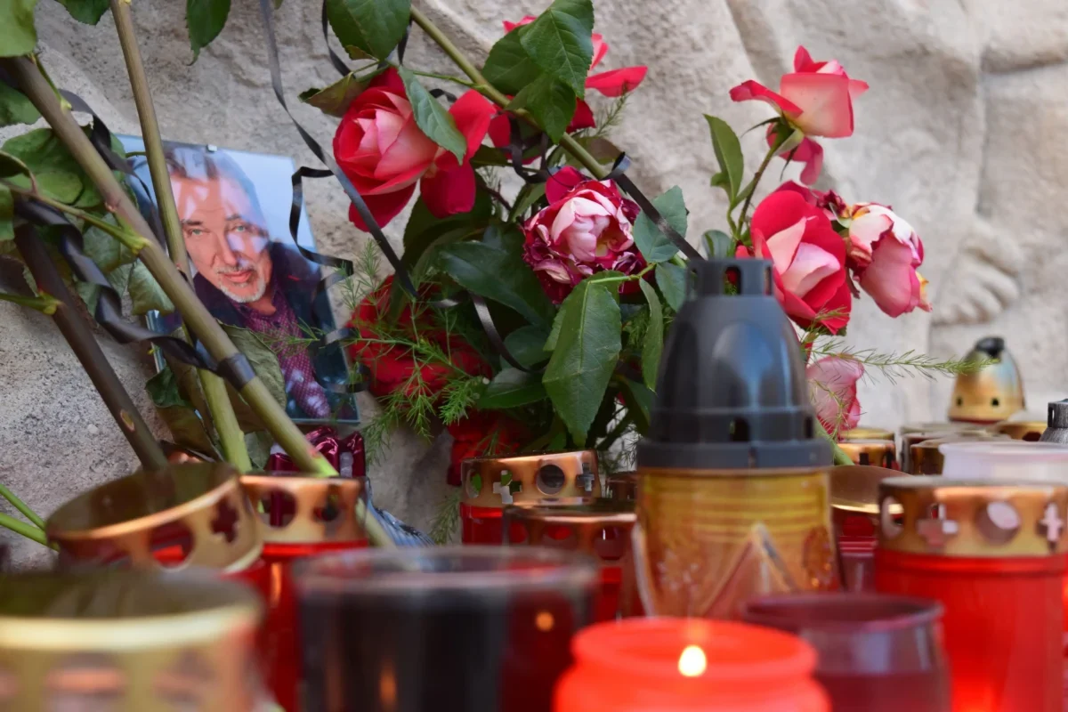Kolem fotky Karla Gotta leží květiny a svíčky.