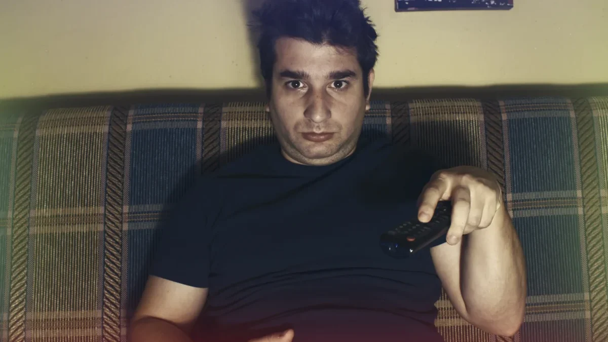 Muž s otráveným výrazem sedí na gauči.