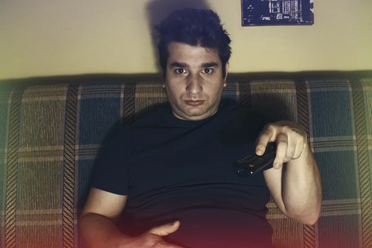 Muž s otráveným výrazem sedí na gauči.