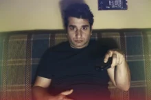 Muž s otráveným výrazem sedí na gauči.