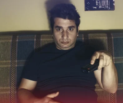 Muž s otráveným výrazem sedí na gauči.