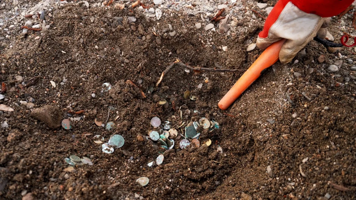 Člověk ze země vyhrabává mince.