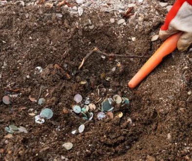 Člověk ze země vyhrabává mince.