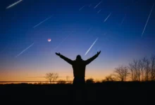 Muž má ruce nahoru a na nebi se míhají komety.