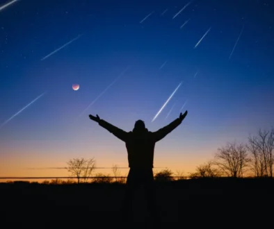 Muž má ruce nahoru a na nebi se míhají komety.