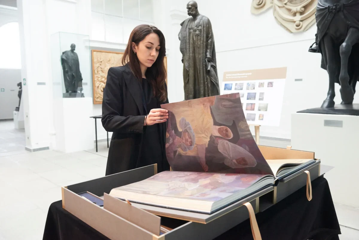 Žena listuje obří knihou.