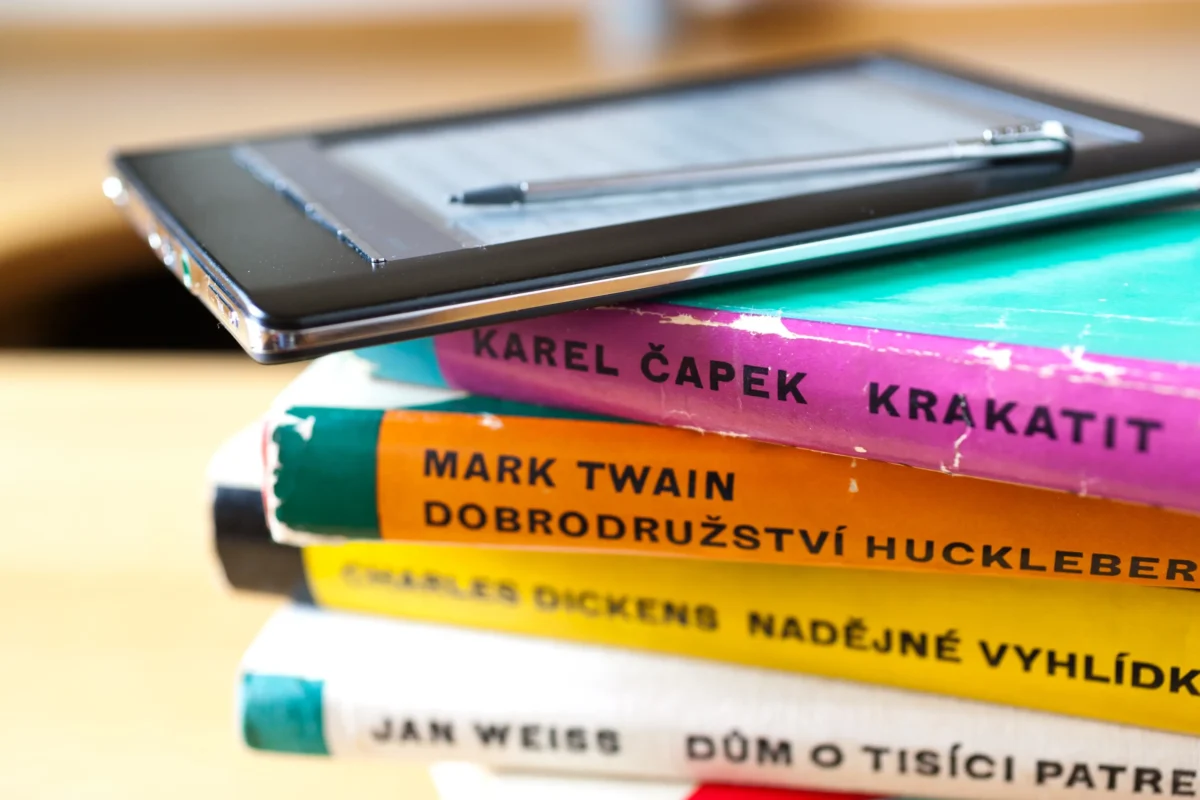 Na sobě leží staré knihy a čtečka. 