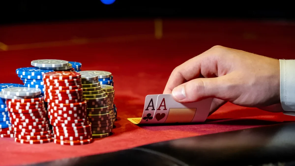 Muž odkrývá karty na pokerovém stole s žetony