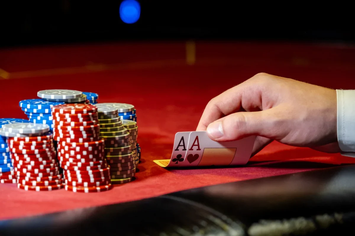 Muž odkrývá karty na pokerovém stole s žetony