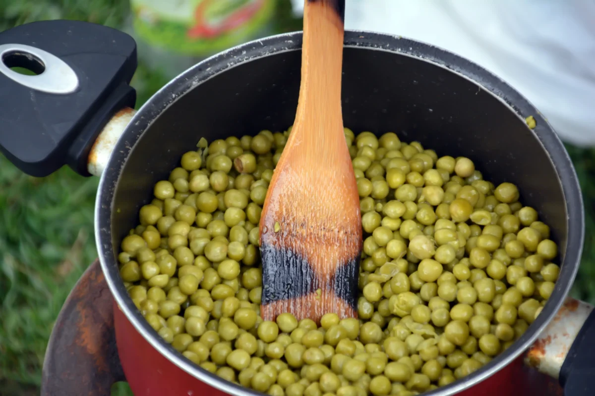 V hrnci je uvařený hrášek a vařečka. 