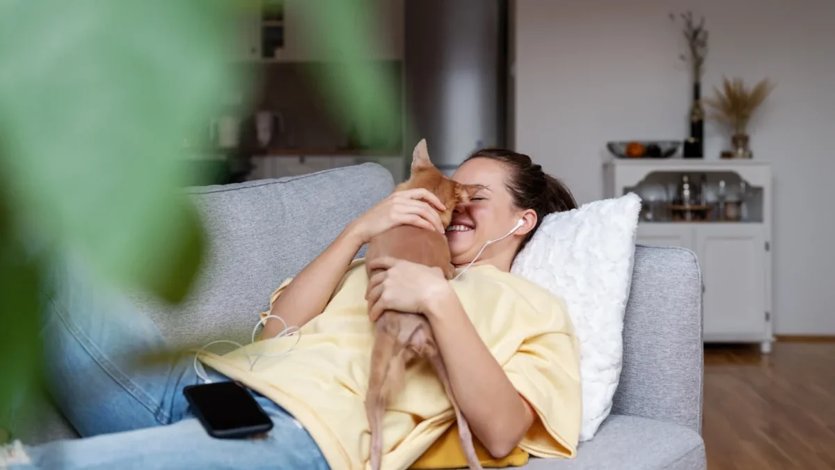 Žena s kočkou leží na pohovce.