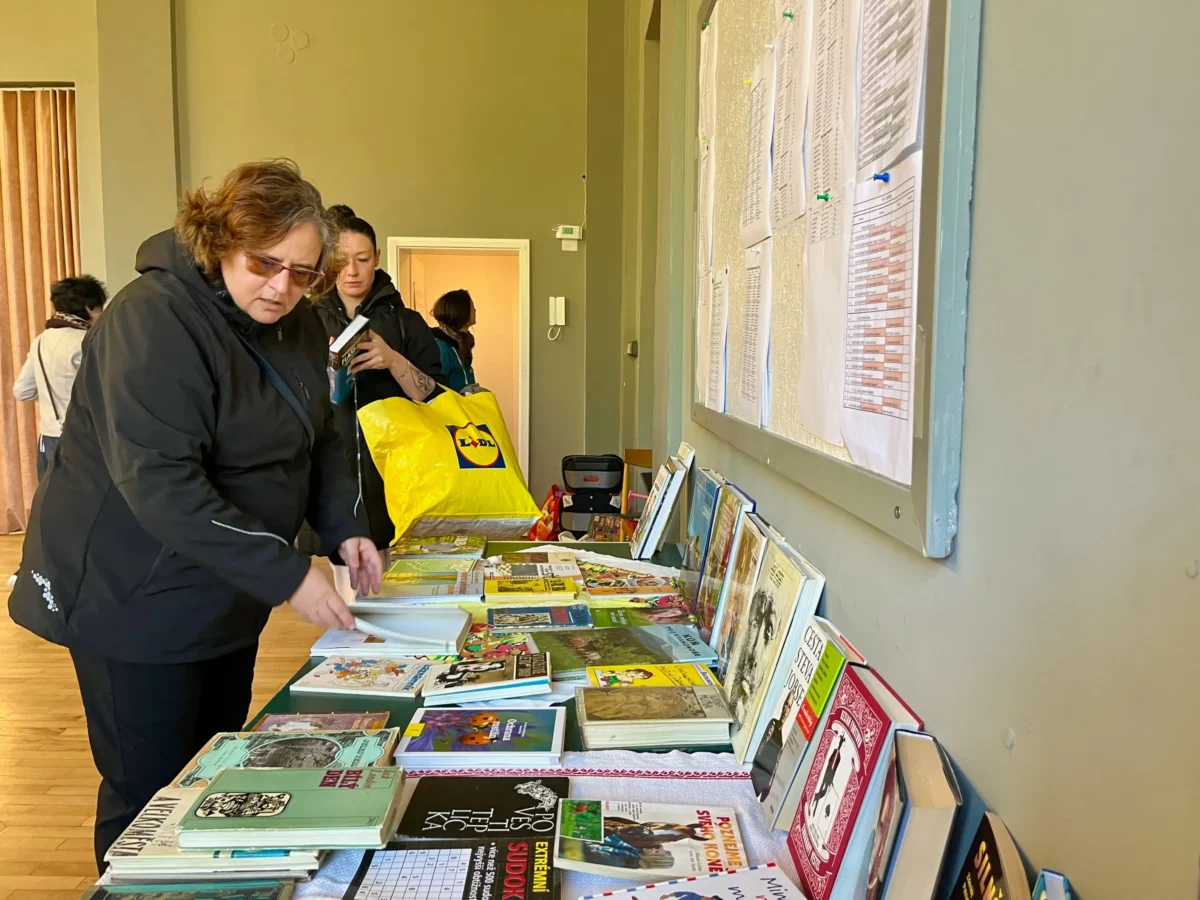 Paní si prohlíží knihy na stole. 