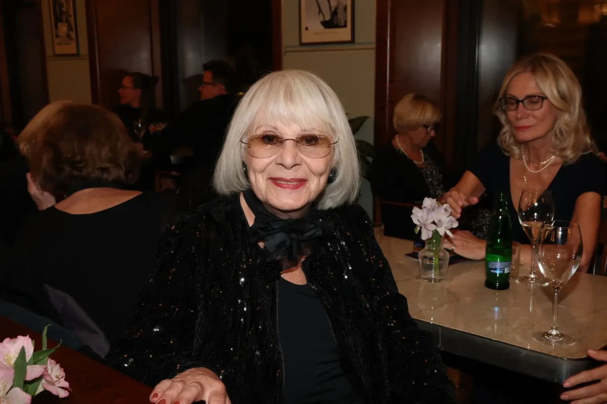 Marie Drahokoupilová sedí u stolu a usmívá se.