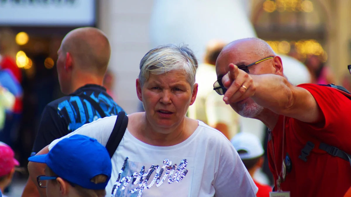 Žena stojí vedle muže, který ukazuje před sebe. 