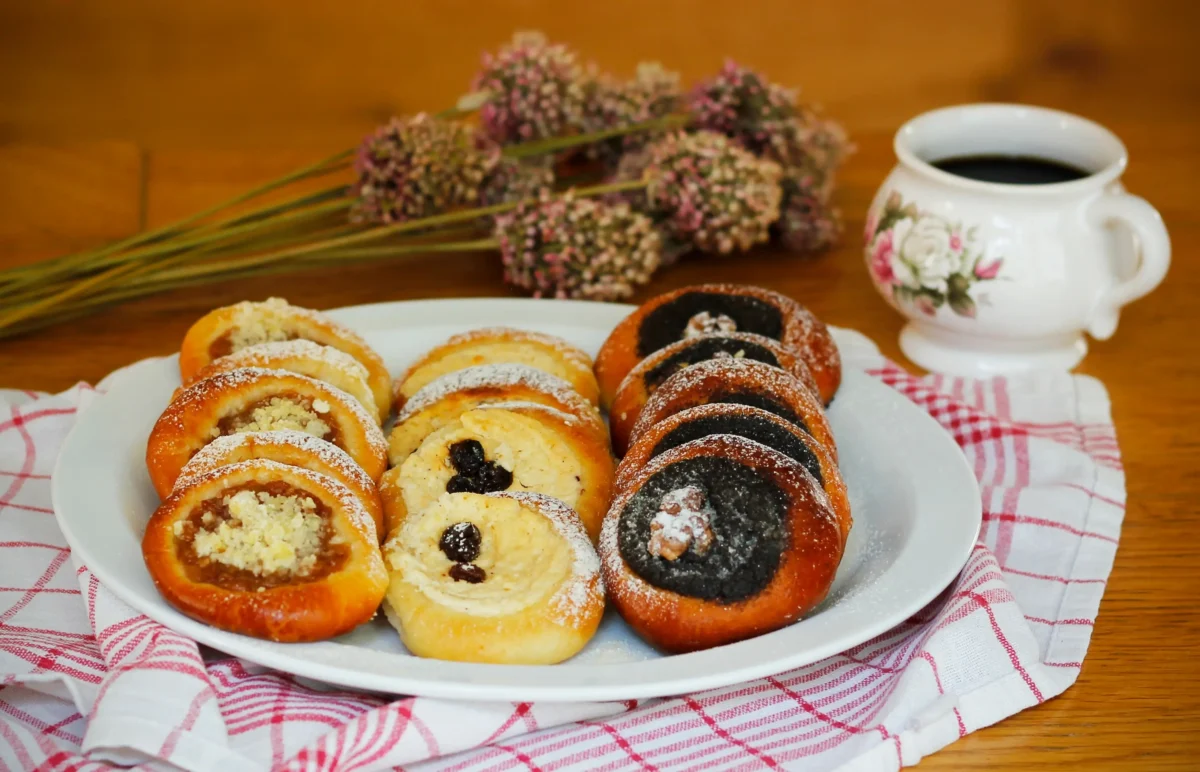 Na talíři jsou koláčky a vedle hrnek s pitím.