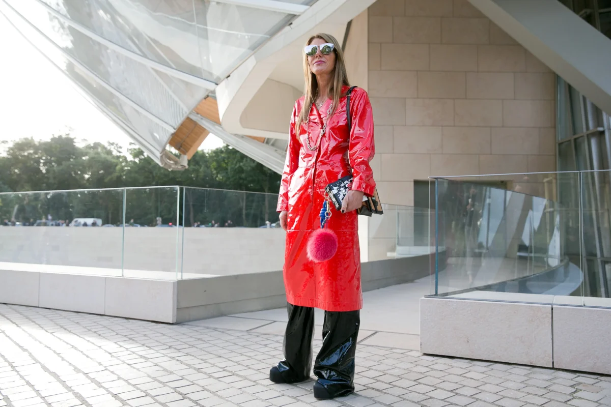 Žena stojí v červeném kabátu venku. 