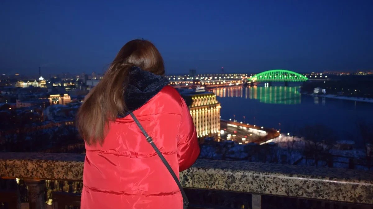 Žena dívající se ve městě na noční oblohu.