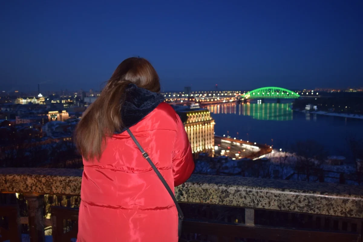 Žena dívající se ve městě na noční oblohu.