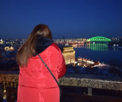 Žena dívající se ve městě na noční oblohu.