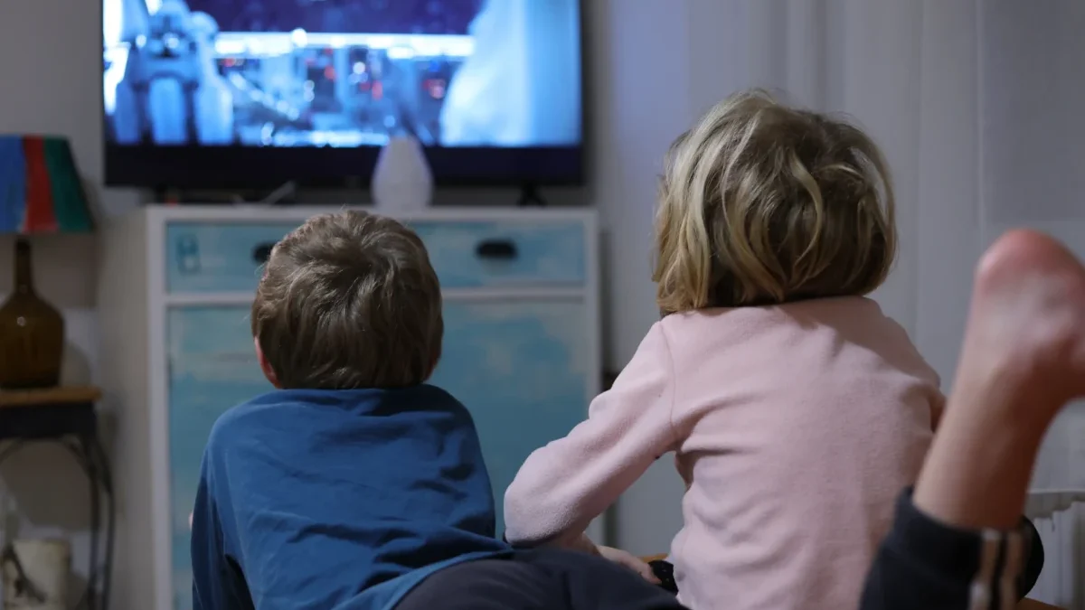 Děti leží u televize.