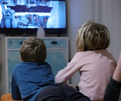 Děti leží u televize.