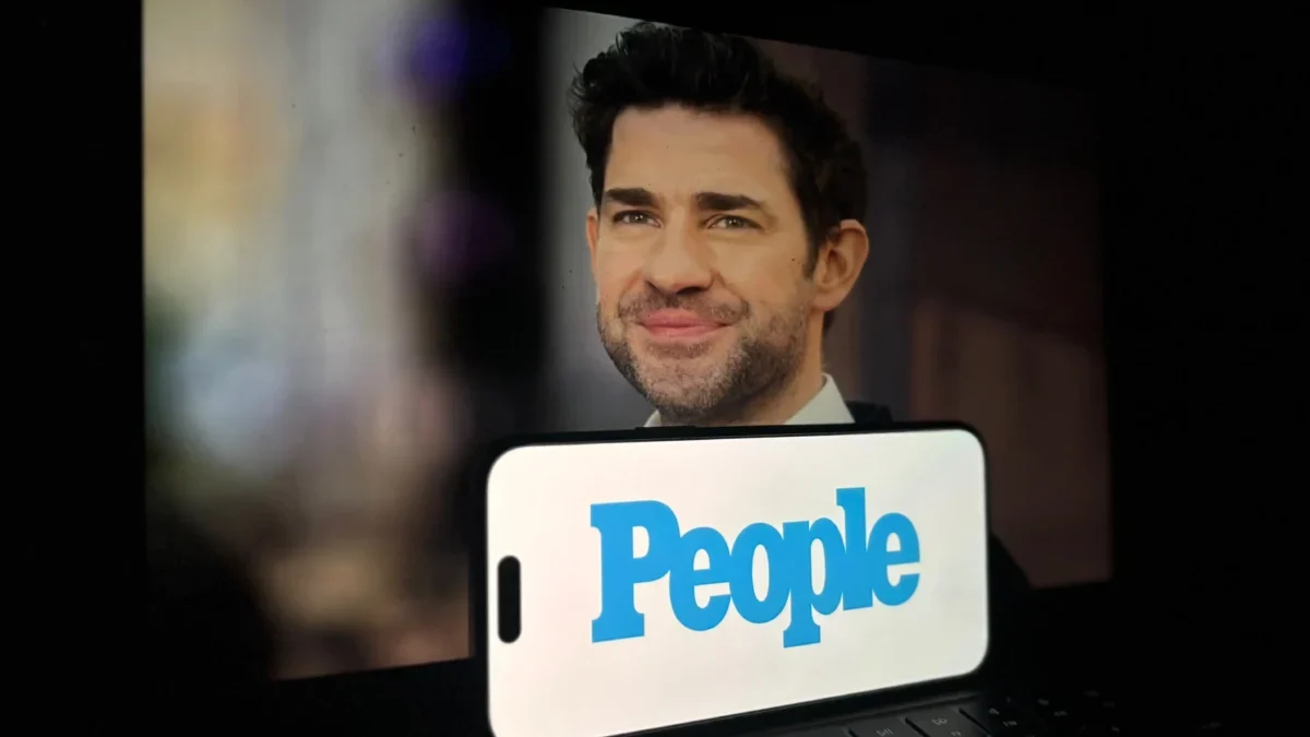 Před notebookem je položený mobil s nápisem People.