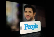 Před notebookem je položený mobil s nápisem People.