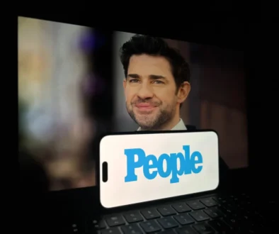 Před notebookem je položený mobil s nápisem People.