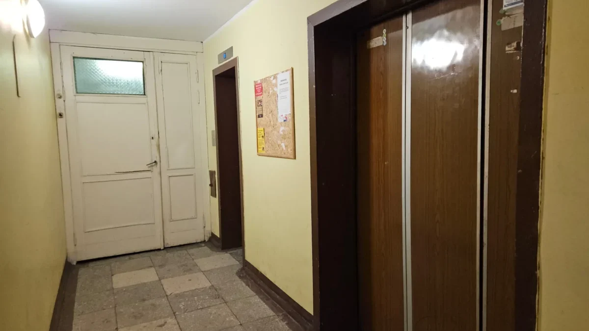 Chodba v paneláku s výtahem a nástěnkou