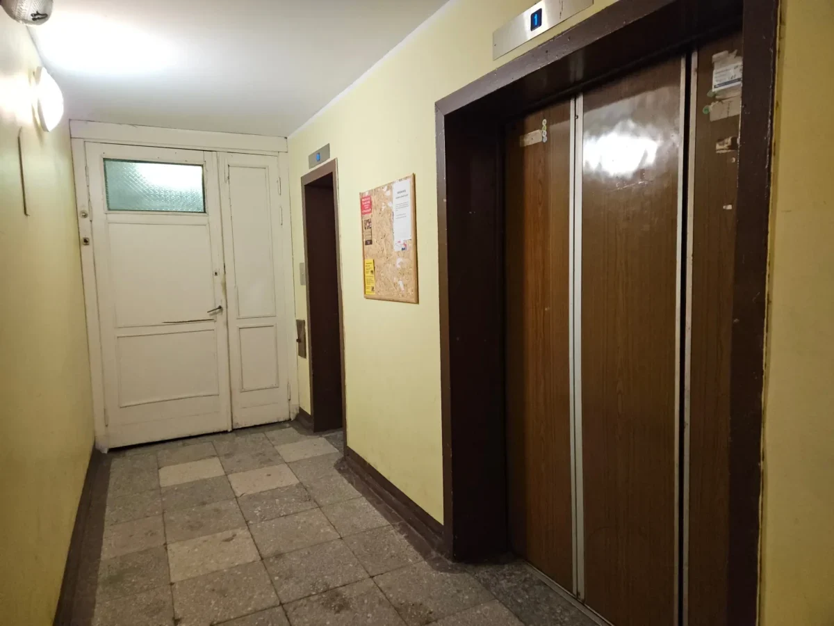 Chodba v paneláku s výtahem a nástěnkou