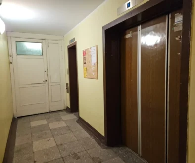 Chodba v paneláku s výtahem a nástěnkou
