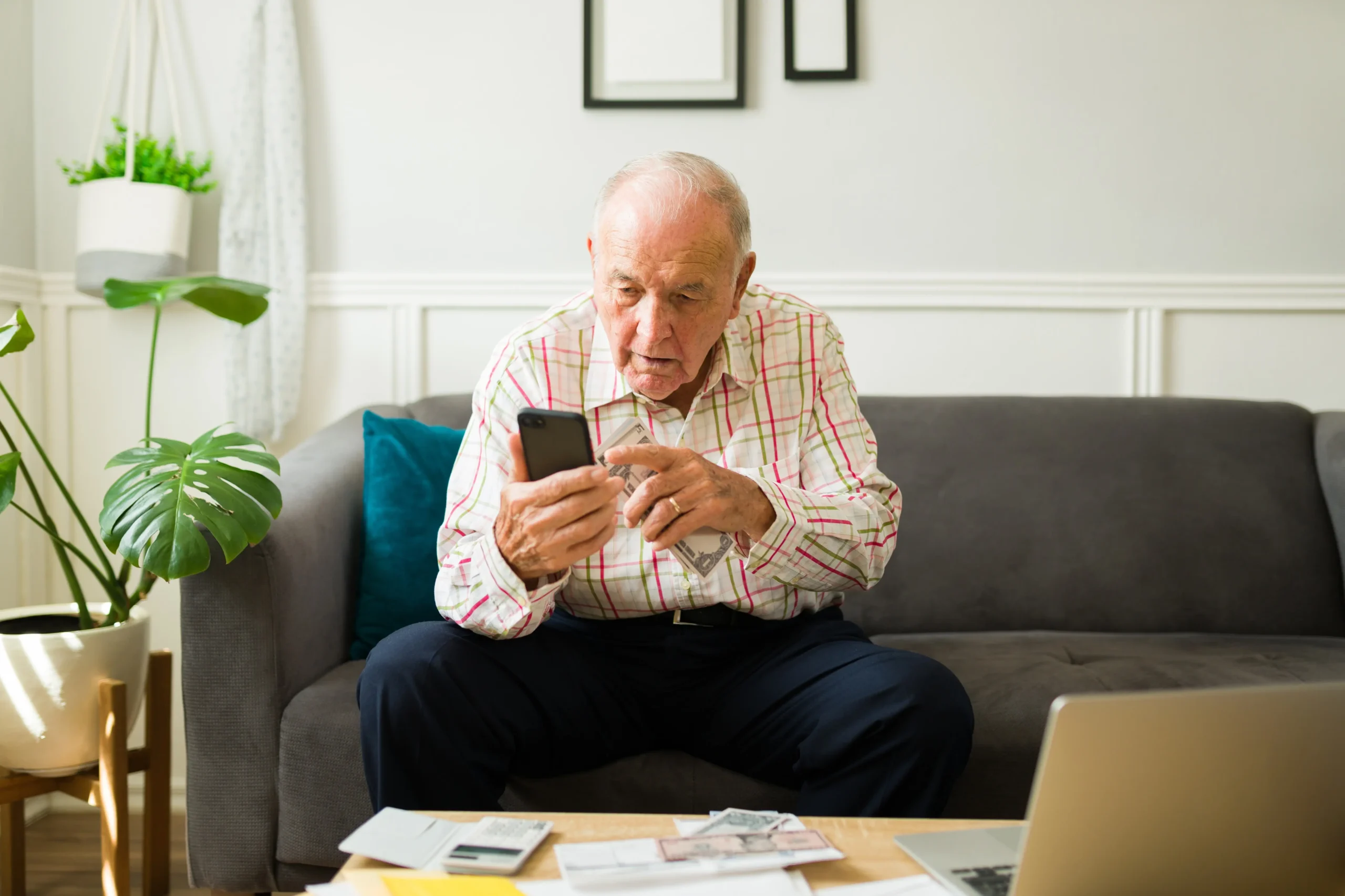 Senior na gauči s telefonem v ruce