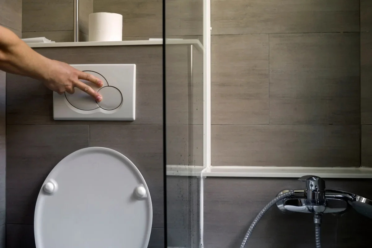 Člověk splachuje toaletu.