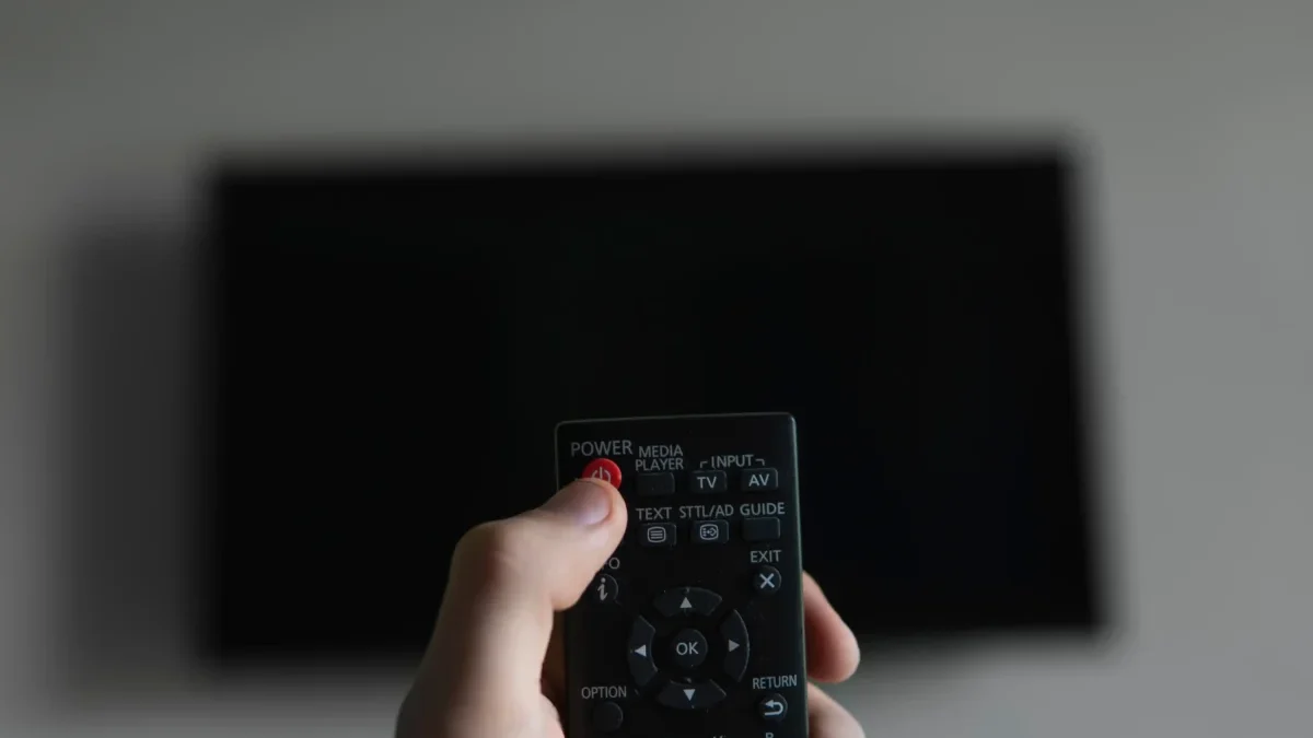 Člověk míří ovladačem na TV.