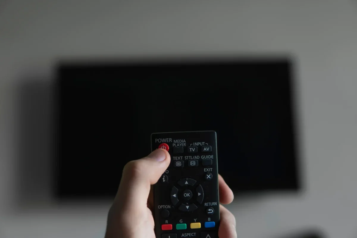 Člověk míří ovladačem na TV.