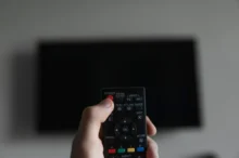 Člověk míří ovladačem na TV.