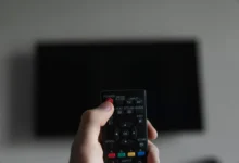 Člověk míří ovladačem na TV.