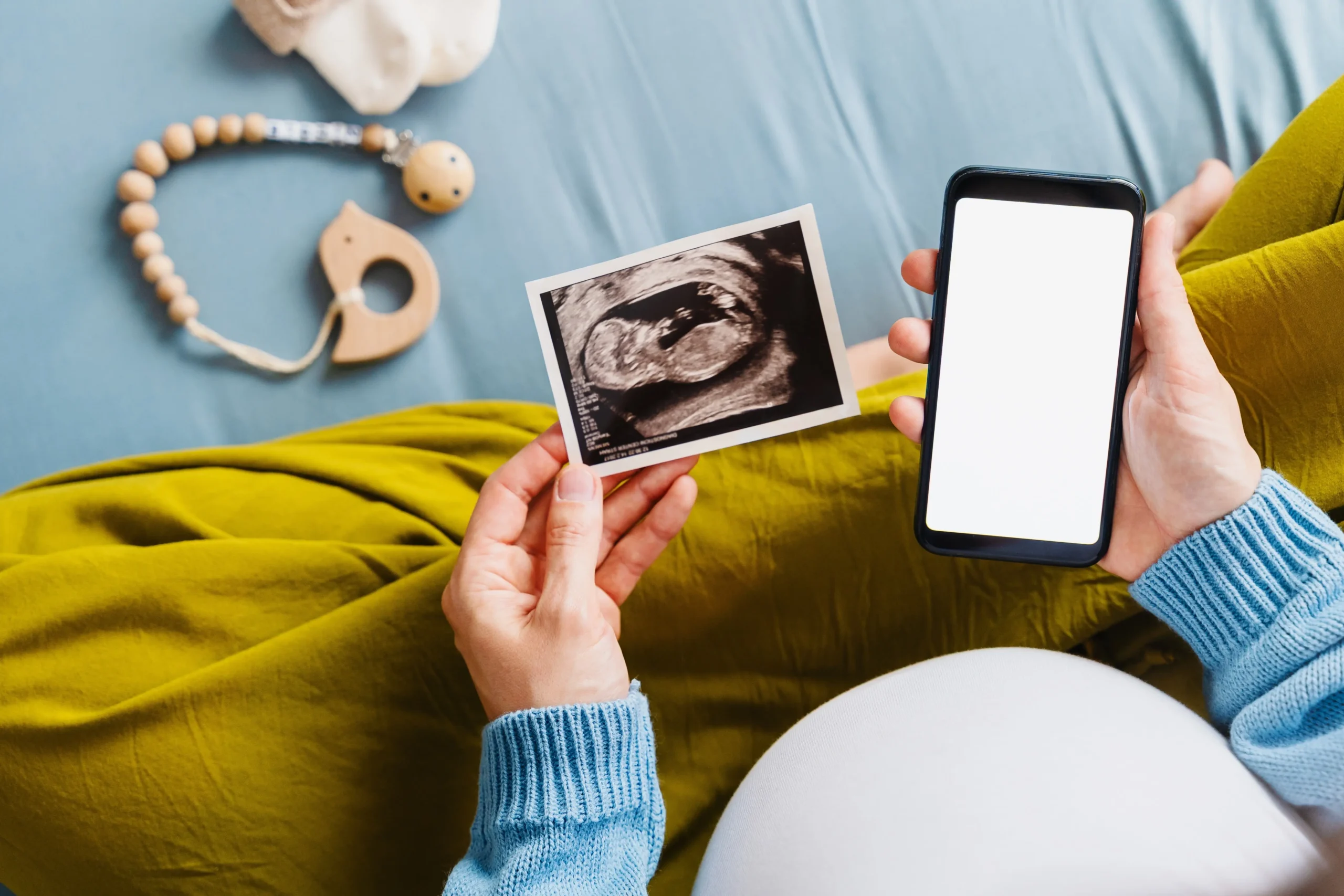 Těhotná žena drží ultrazvuk a mobilní telefon 