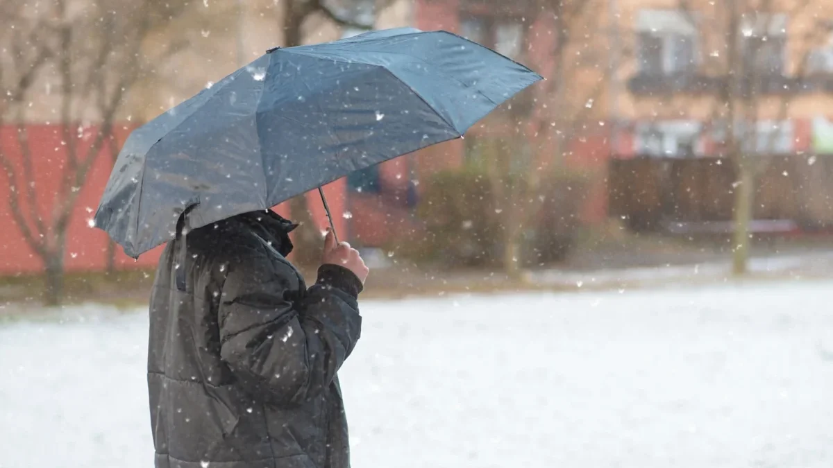 Muž stojí venku pod deštníkem.