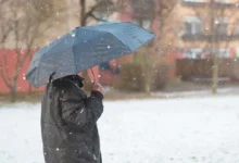 Muž stojí venku pod deštníkem.